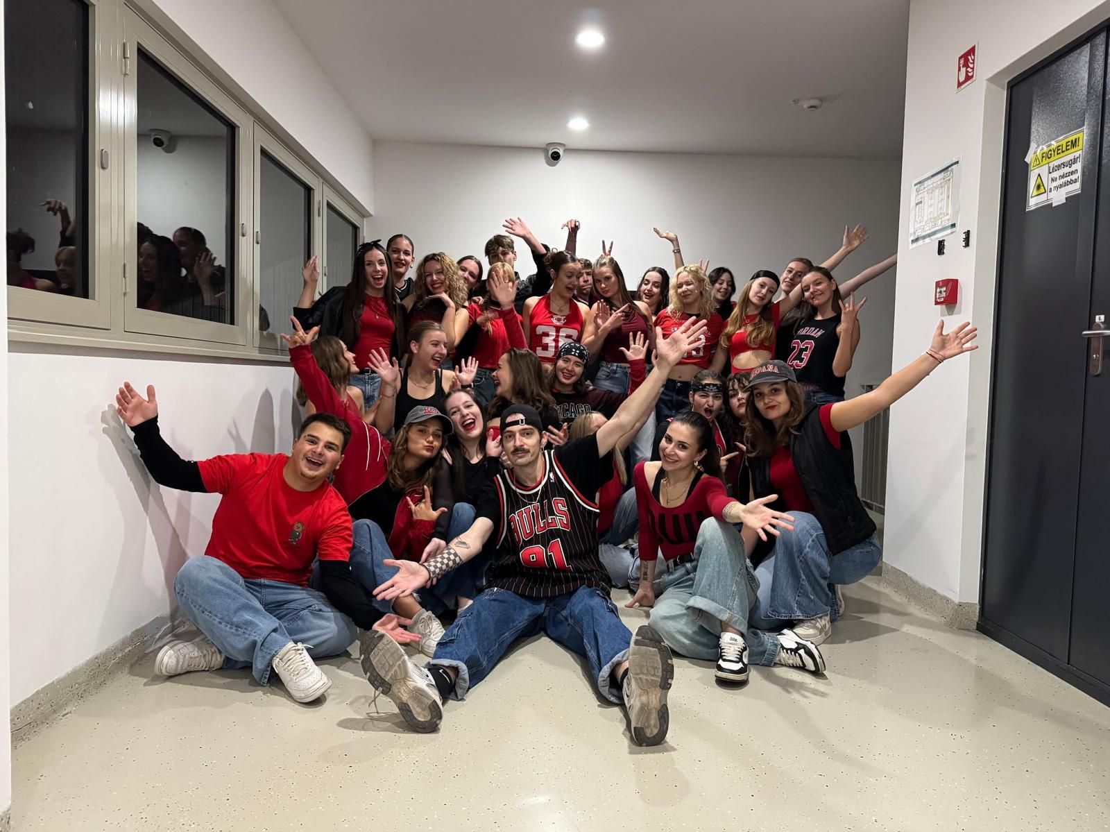 The hip-hop dance team in red and black outfits, posing together with arms raised